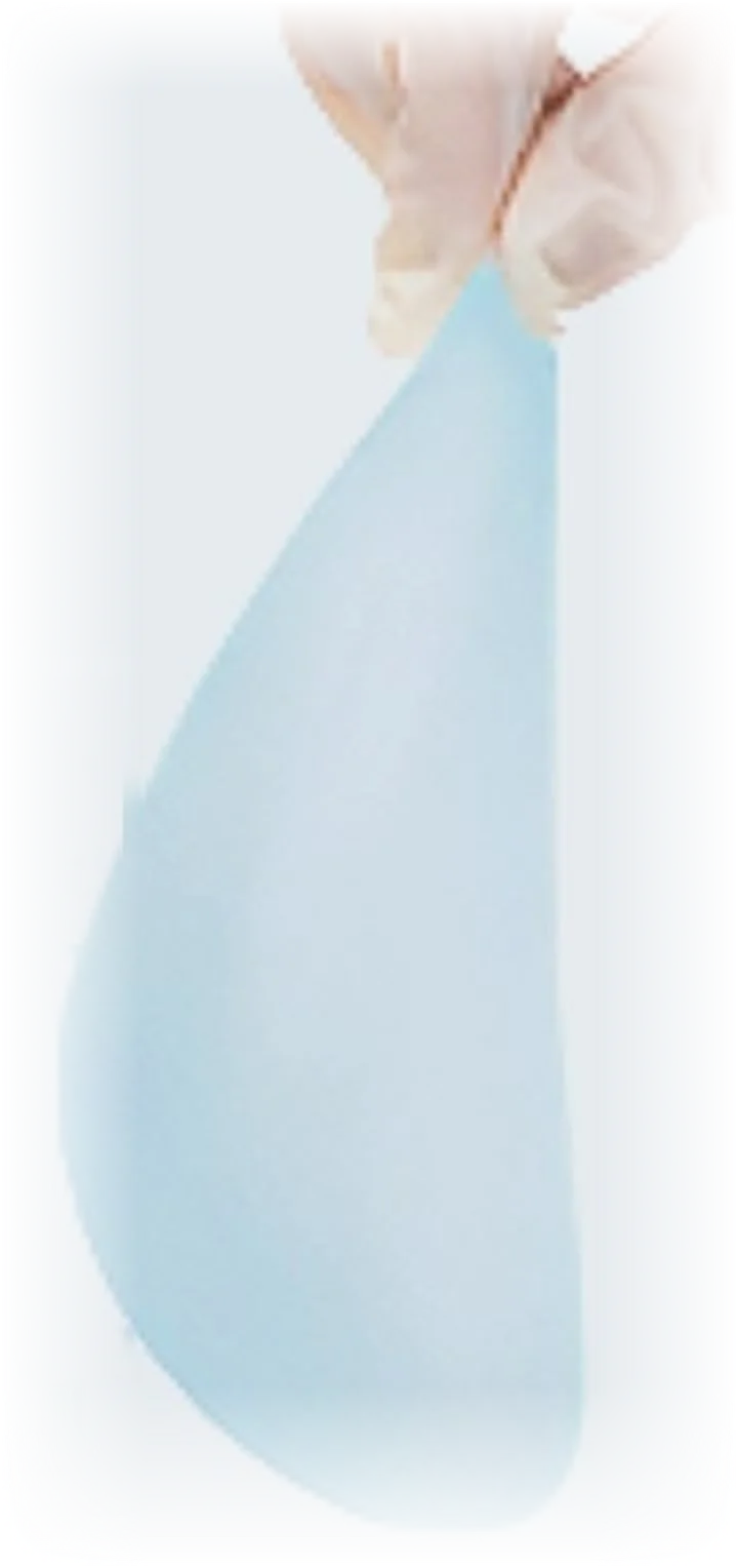 A gloved hand holding a teardrop-shaped breast implant